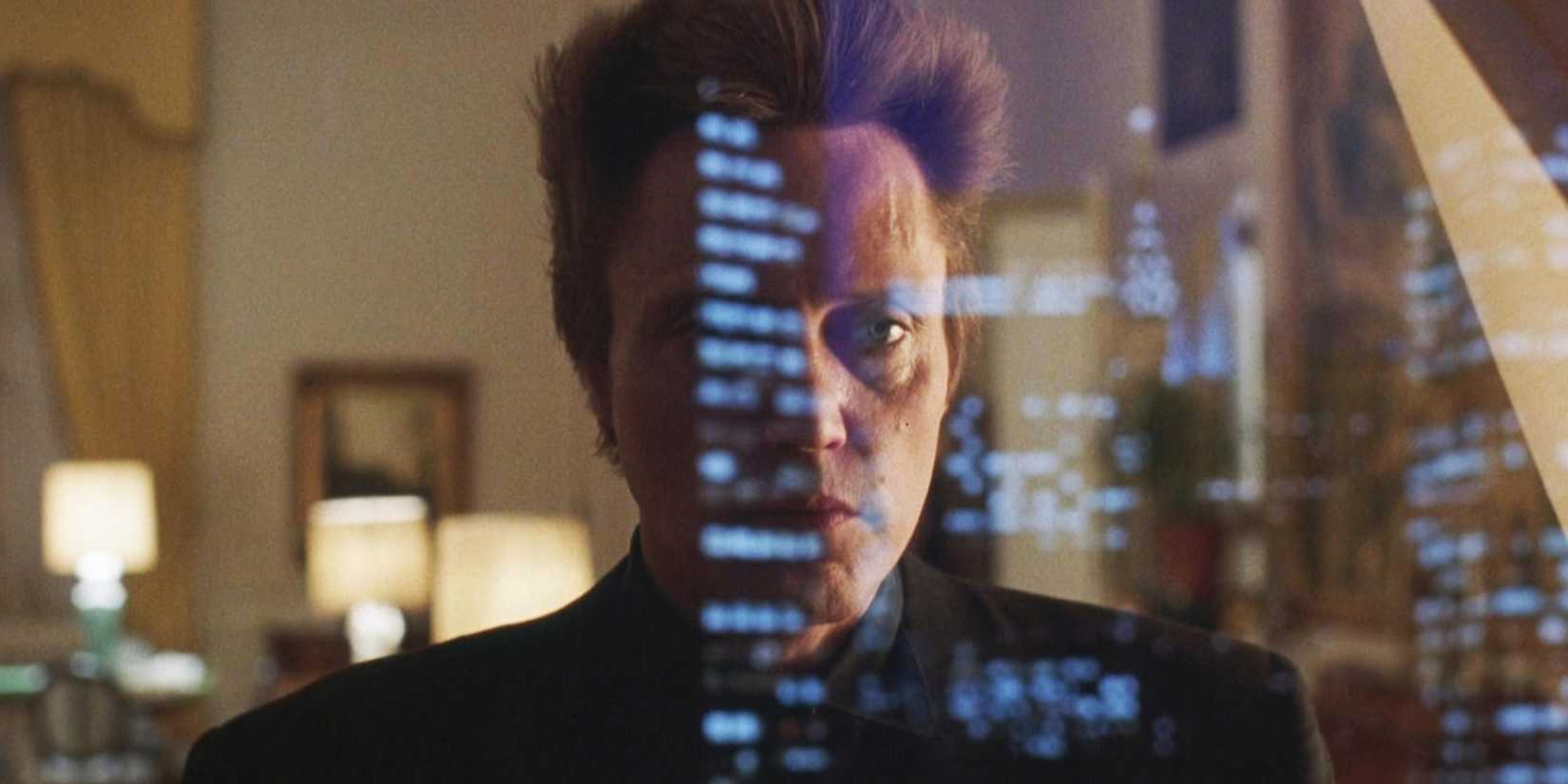Christopher Walken standing in front of a window with a city reflected in King Of New York