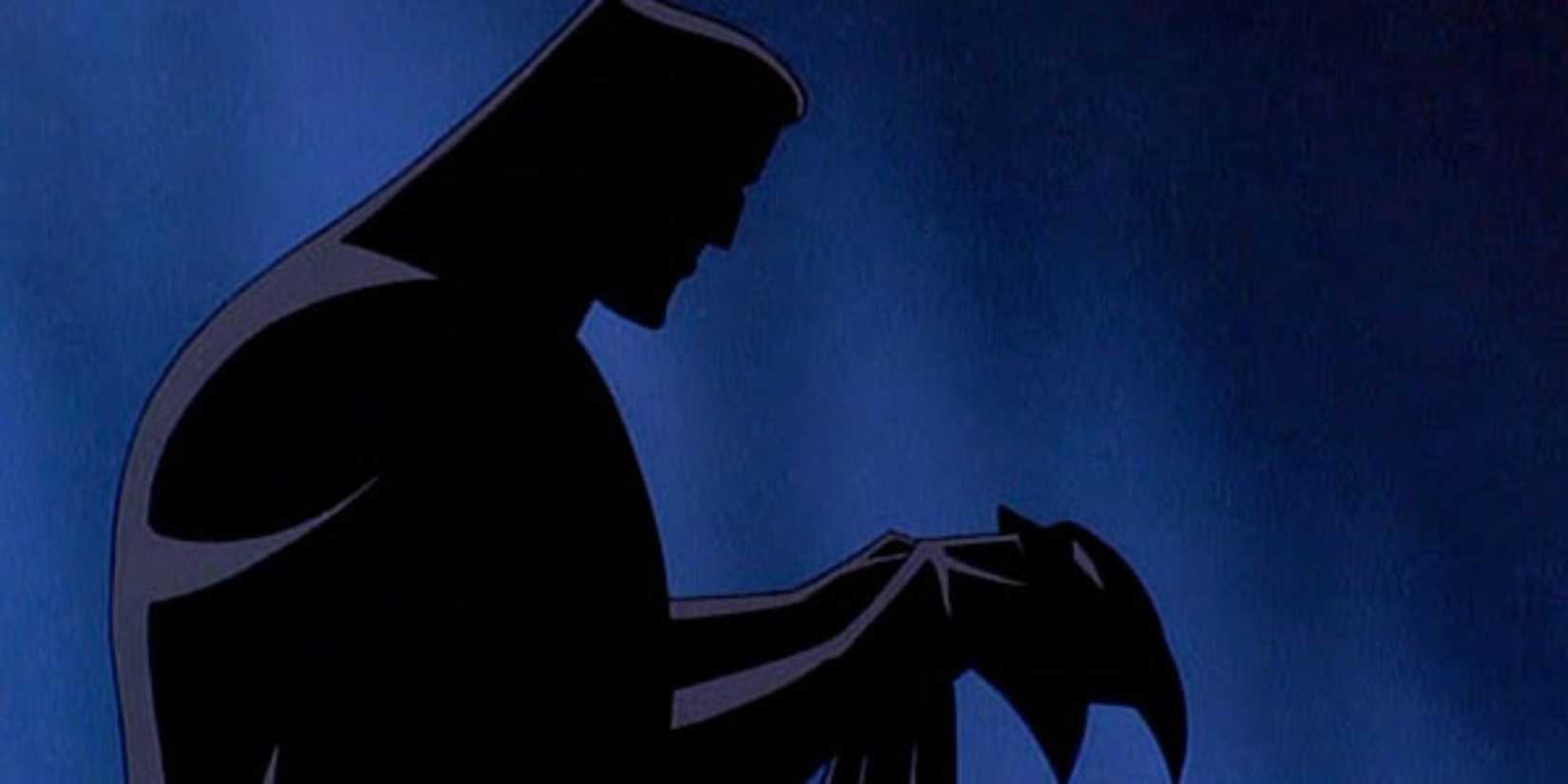 Silhouette of Bruce Wayne holding his Batman mask, from Batman: Mask of the Phantasm. 