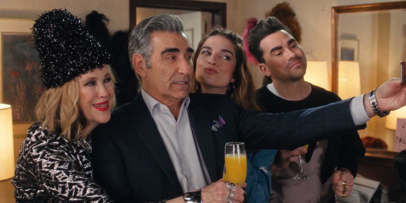 The Roses in Schitt's Creek huddled together greeting someone.