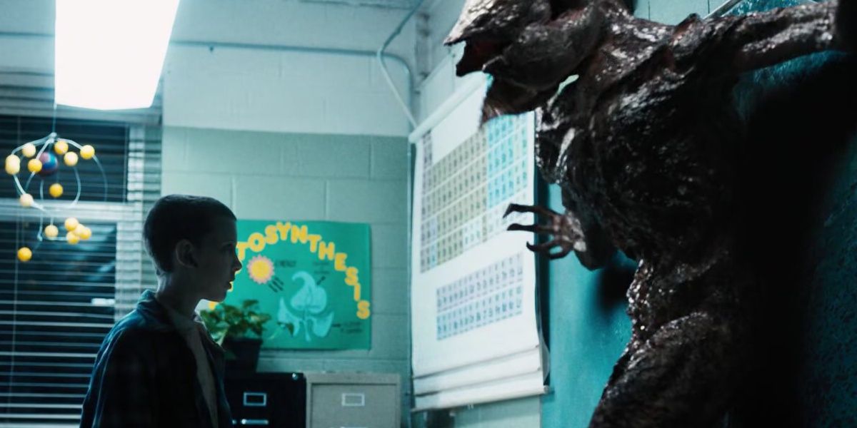 In a blue toned classroom, Millie Bobbie Brown as Eleven stares down the Demogorgon. 