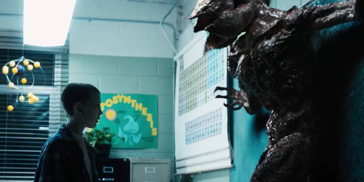 In a blue toned classroom, Millie Bobbie Brown as Eleven stares down the Demogorgon.