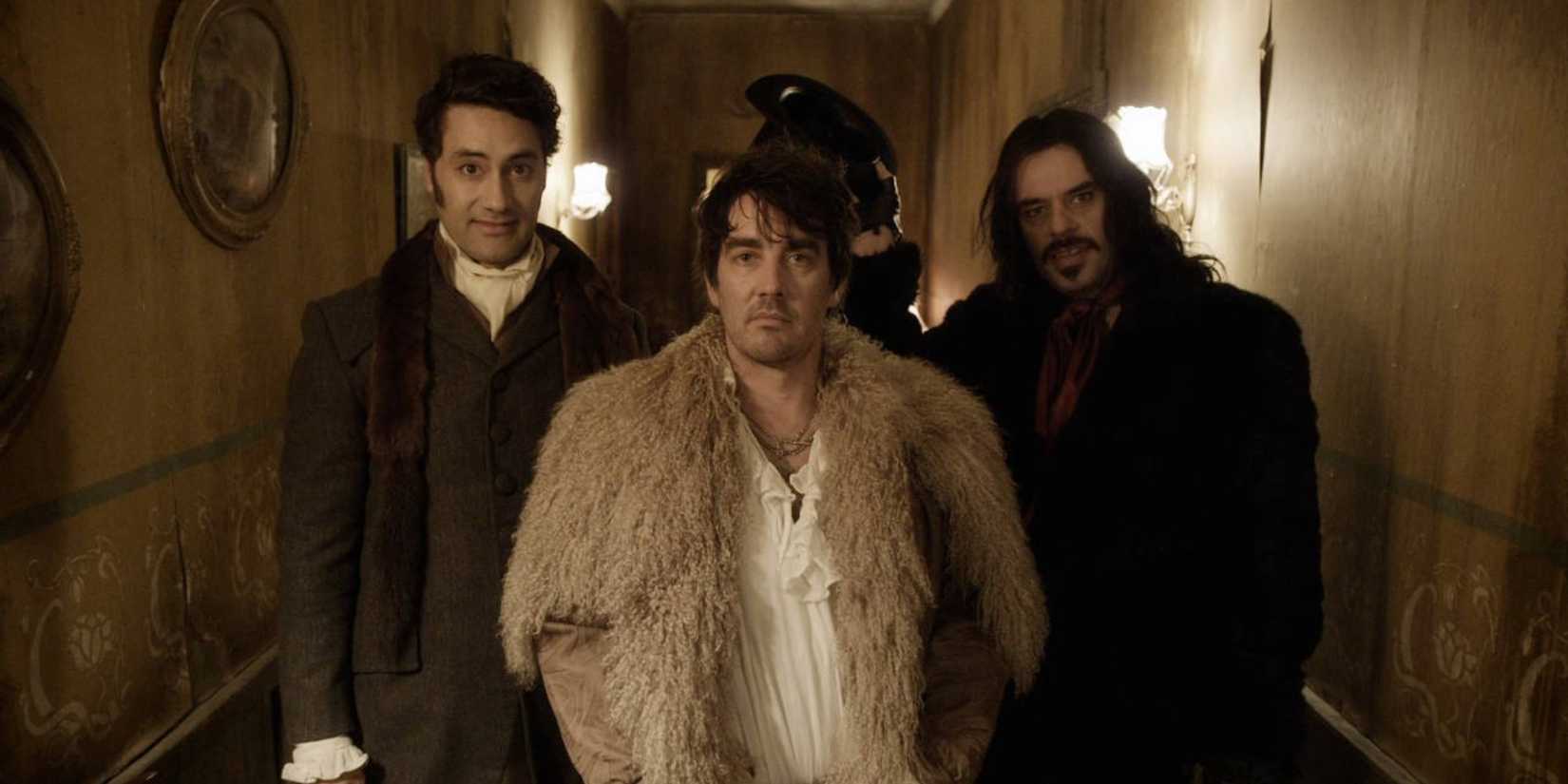 Taika Waititi, Jemaine Clement and Jonathan Brugh in a hallway looking at the camera in What We Do in the Shadows movie