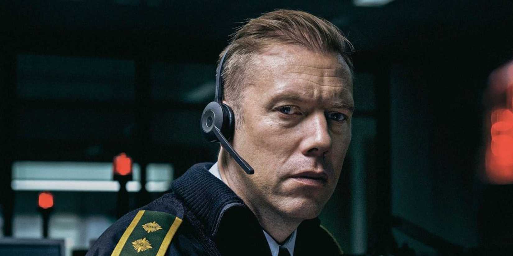 A man wearing a telephone headset looks to camera in this still from The Guilty