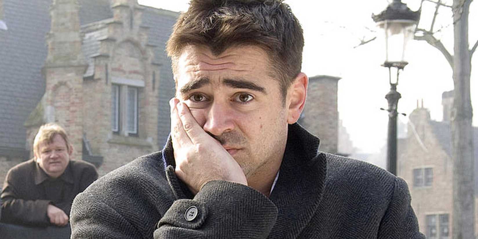 Colin Farrell as Ray looks pensive while Brendan Gleeson as Ken watches him from the background in In Bruges