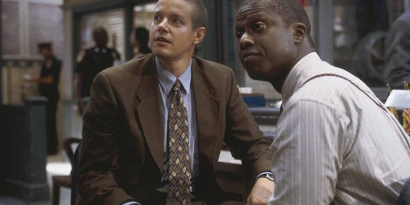 Two men in suits in a police station look up in a scene from Homicide: Life on the Street