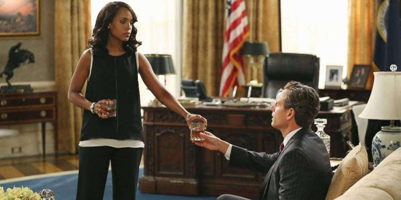 Kerry Washington as Olivia Pope handing Tony Goldwyn as Fitzgerald Grant a drink in the Oval Office in Scandal.