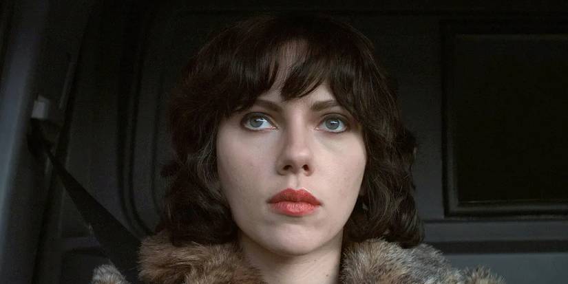 Laura (Scarlett Johansson) duduk dan jam tangan dari kursi depan kendaraan. 