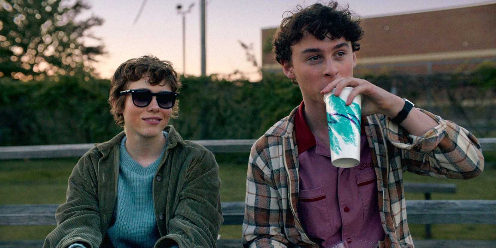 Sophia Lillis & Wyatt Oleff sit at a park bench and look in the same direction in I Am Not Okay With This.