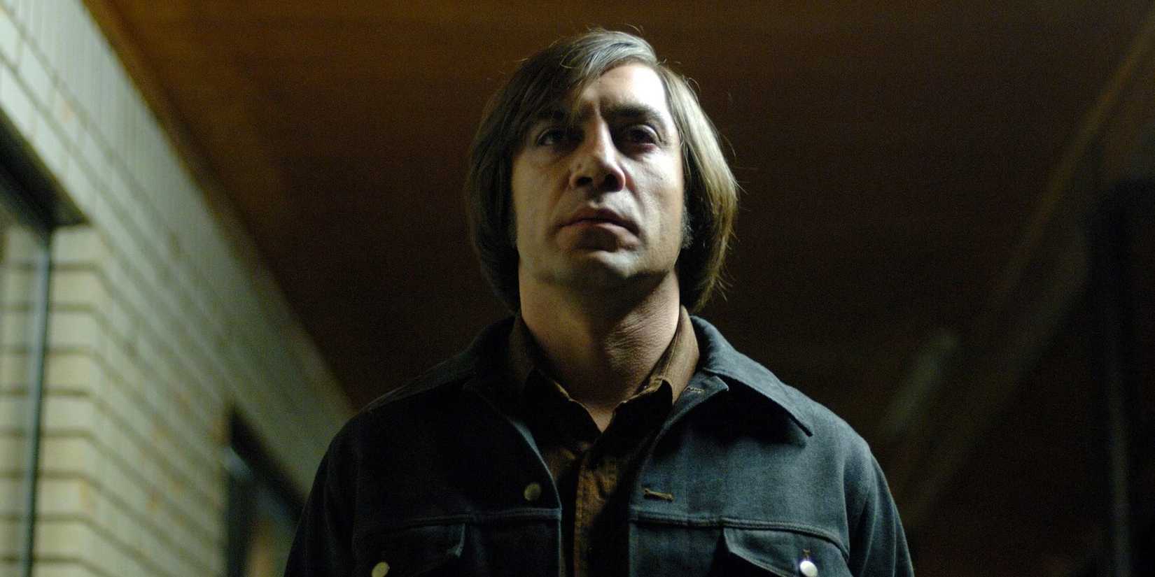 Anton Chigurh looking ahead while walking down a hall in No Country For Old Men.