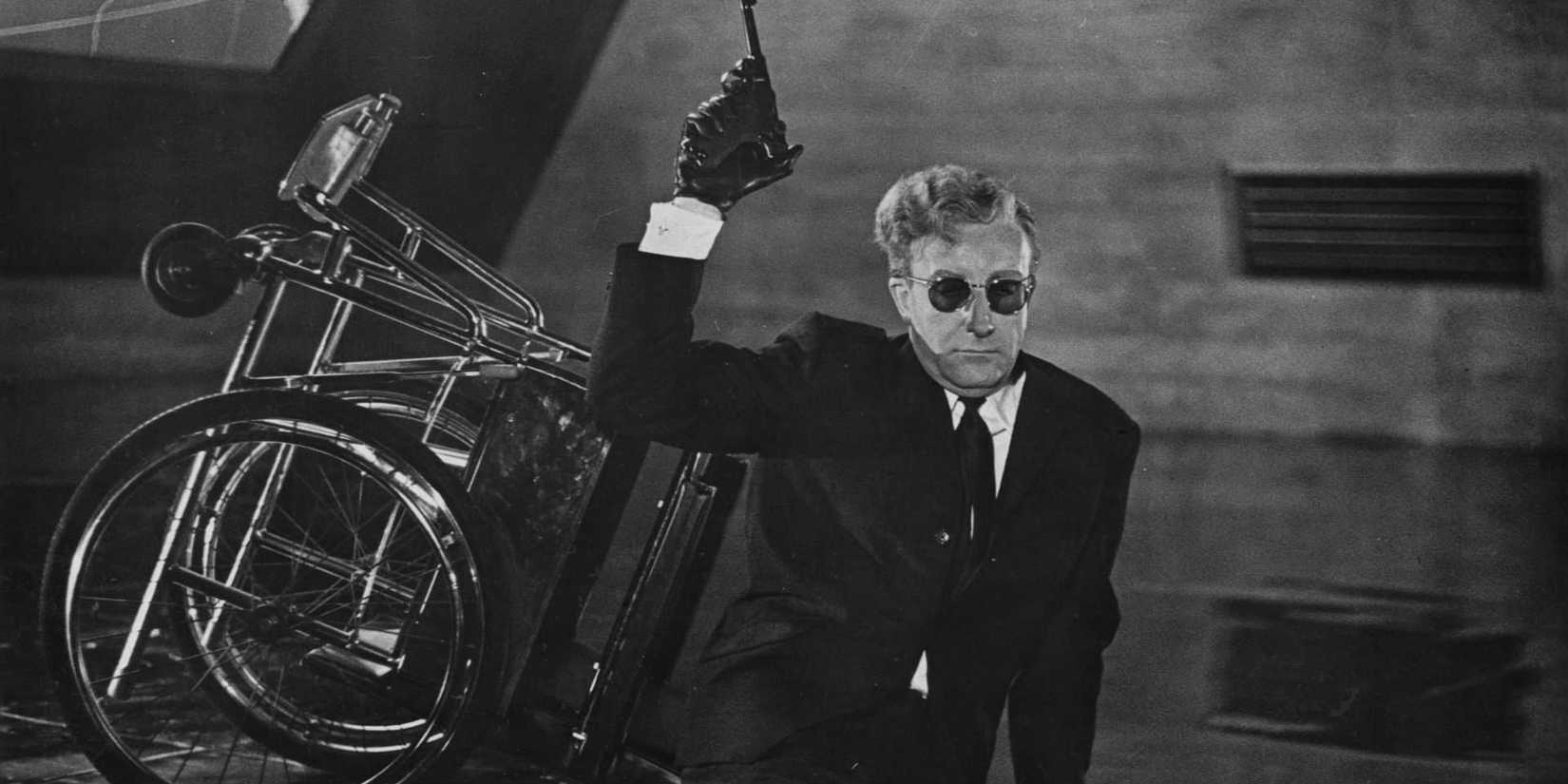 Dr Strangelove holding a cane up while sitting on the floor in Dr Strangelove