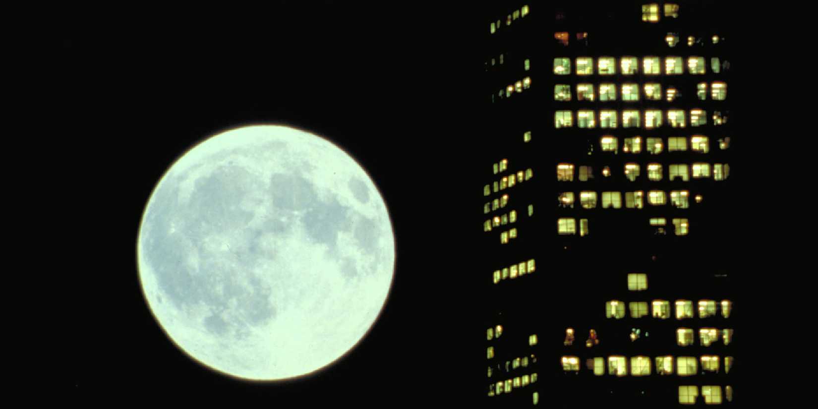 The Moon beside a building at night in Koyaanisqatsi