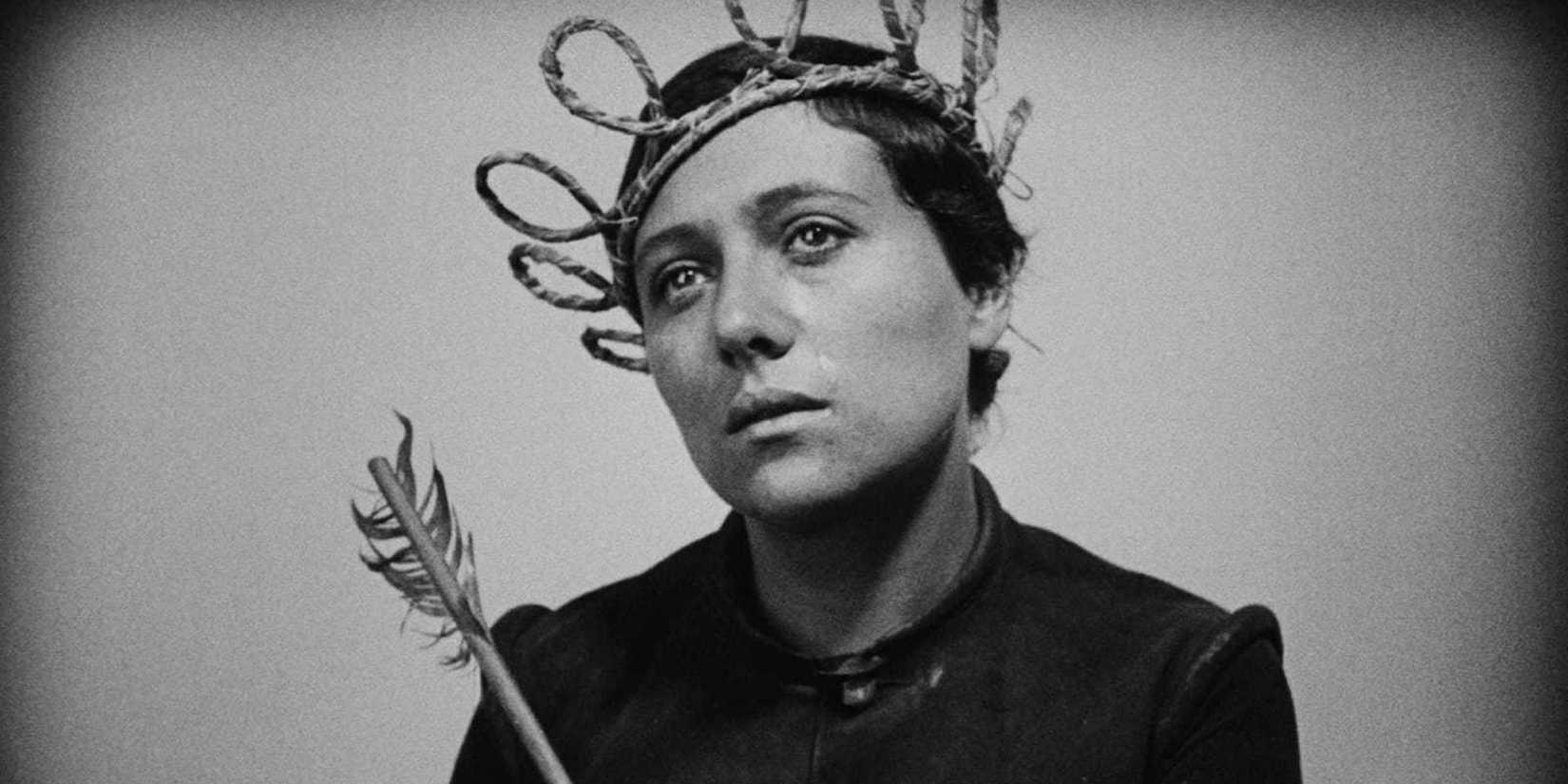 Joan of Arc looking despondent while wearing a crown and holding a scepter in The Passion of Joan of Arc.