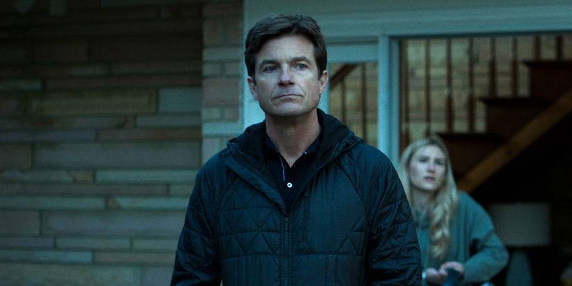 Jason Bateman di Ozark berdiri di dekat pintunya, putrinya di latar belakang.