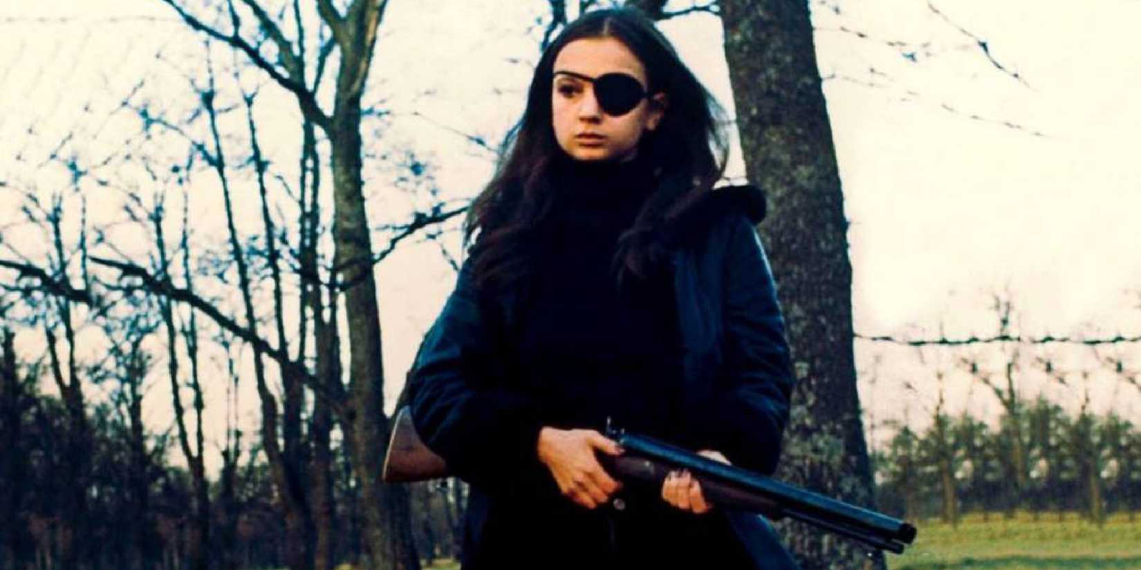 Christina Lindberg as Madeleine holding a gun while standing outside in Thriller_ A Cruel Picture (1973)