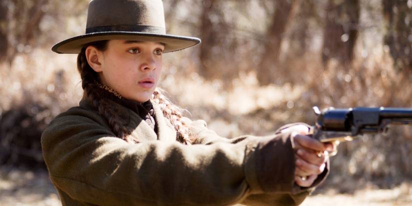 Mattie Ross pointing a gun at something off-camera while looking scared in True Grit.