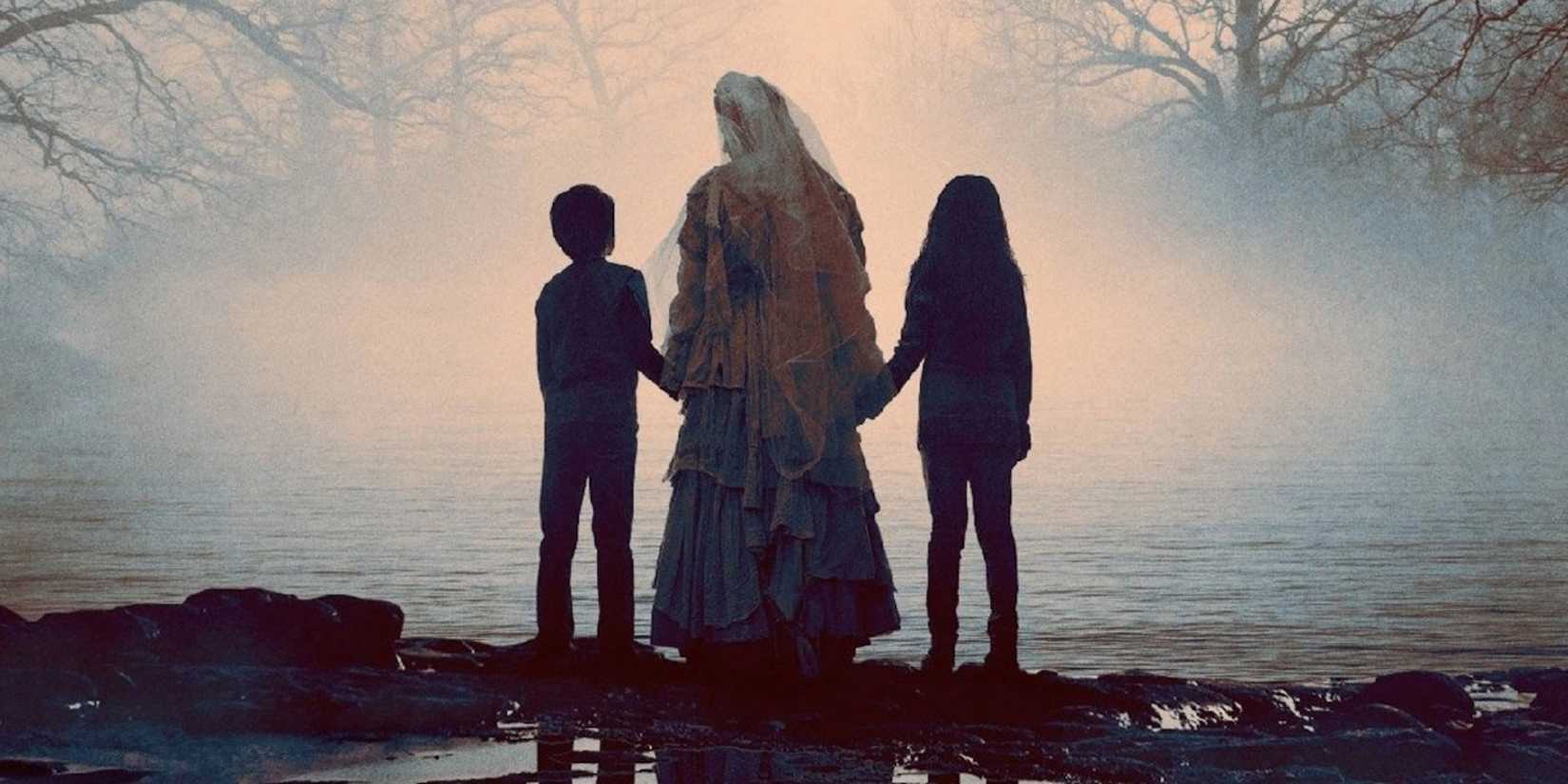 La Llorona holding two children by the hand in a misty lake in The Curse of La Llorona