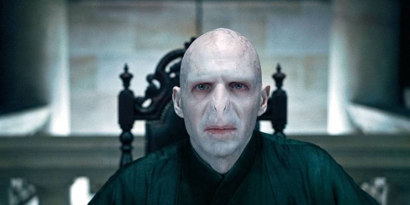 Lord Voldemort, played by Ralph Fiennes, sitting with his Death Eaters in 'Harry Potter and the Deathly Hallows: Part 1.'