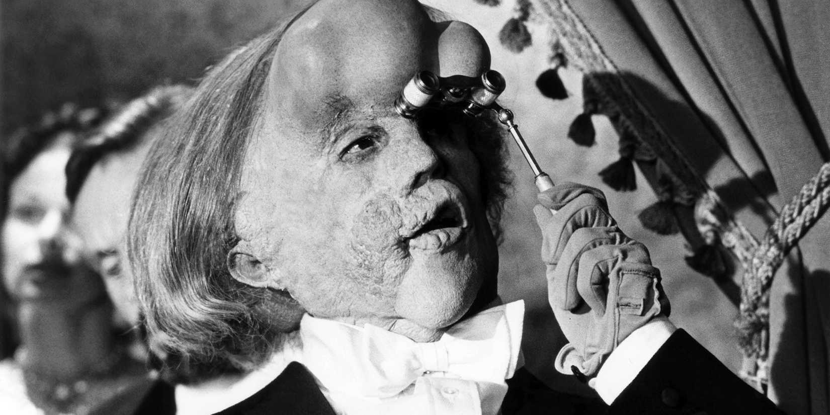 John Hurt as John Merrick in a tuxedo looking through Opera glasses in 'The Elephant Man'