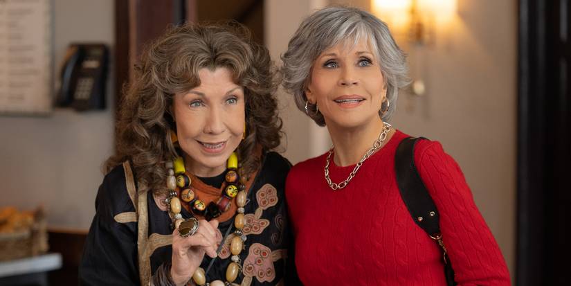 Grace (Jane Fonda) and Frankie (Lily Tomlin) standing together and smiling in Grace and Frankie
