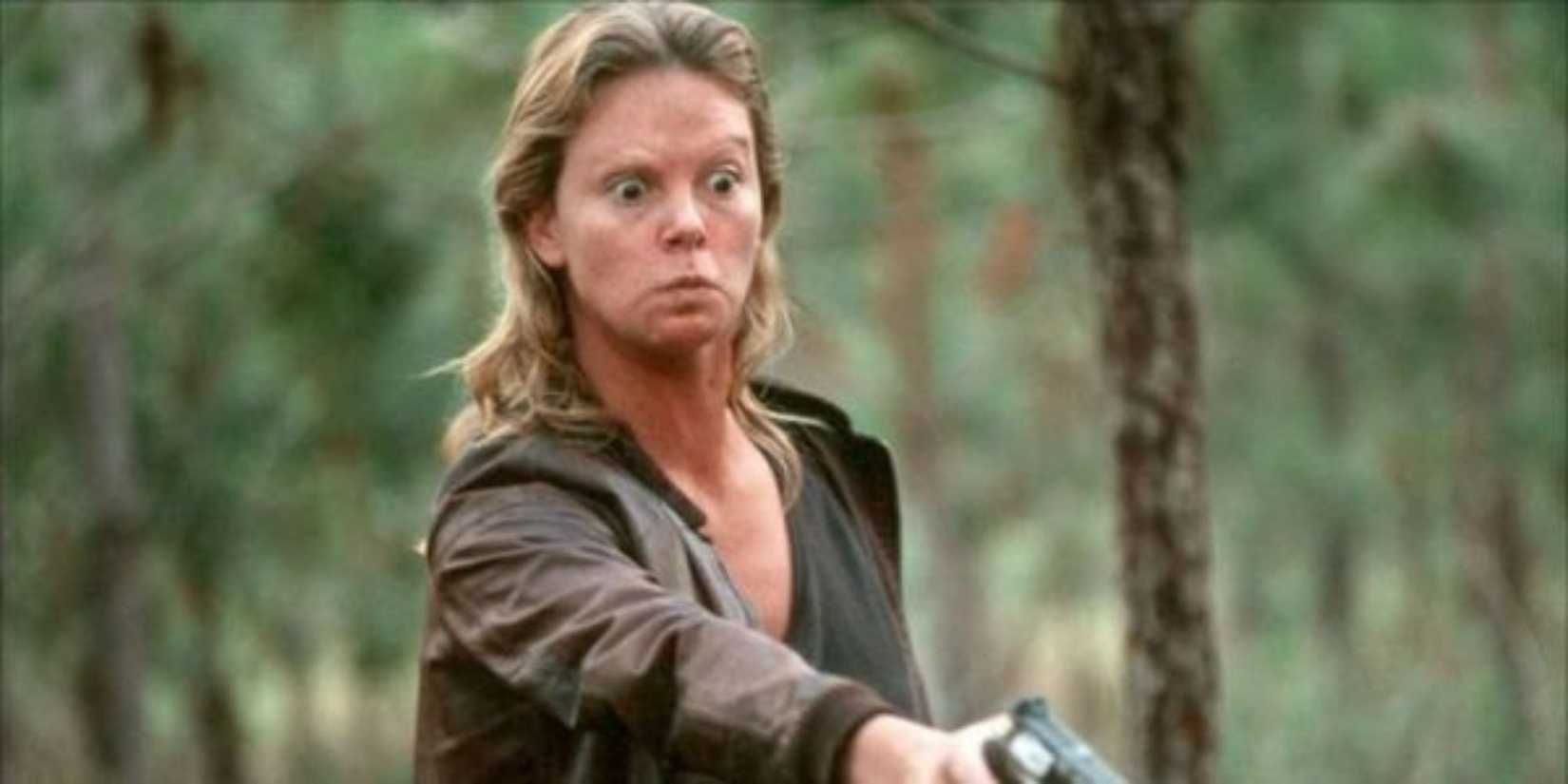 Charlize Theron as Aileen Wuornos aiming a gun down at someone in Monster