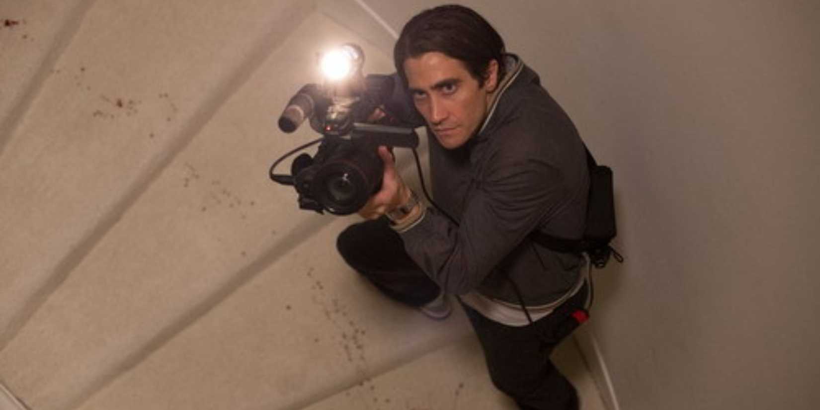 Lou Bloom walking up the stairs holding a camera in 'Nightcrawler'