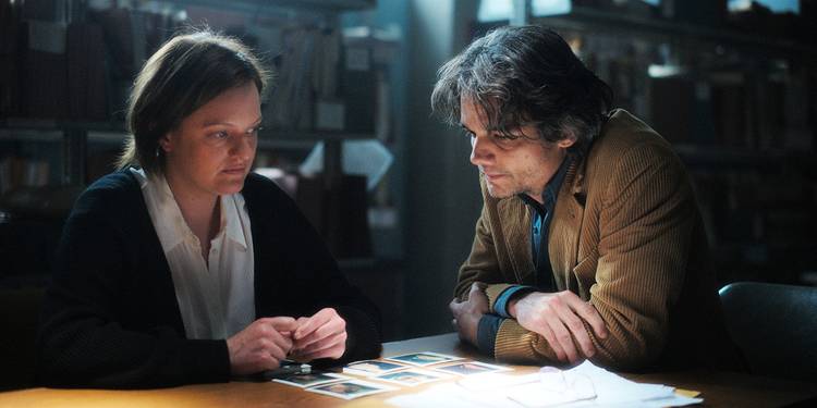 Elisabeth Moss and Wagner Moura look at photos spread before them on a table in Shining Girls.