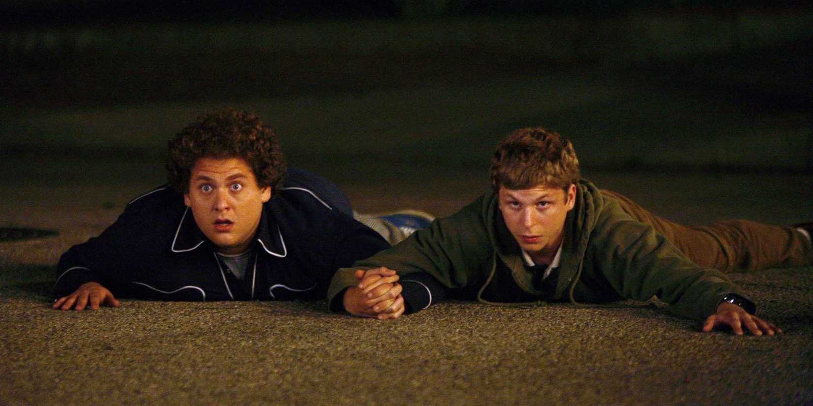 Jonah Hill and Michael Cera holding hands on the ground in Superbad.