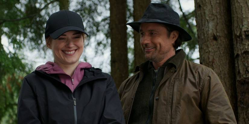 The main characters smile, wearing coats and hats in the woods in Virgin River.