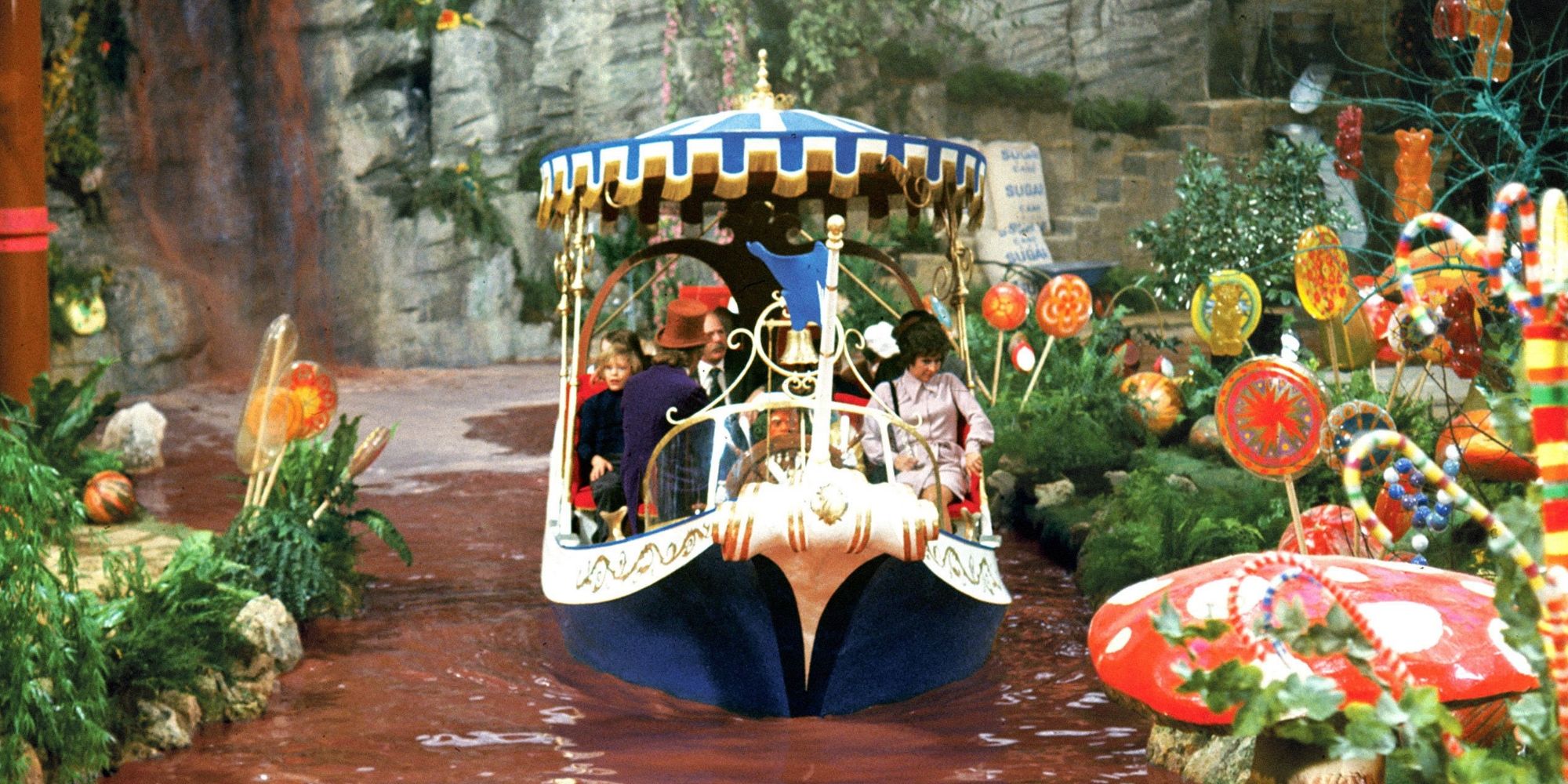 Wonka and the ticket winners ride a boat down a chocolate river