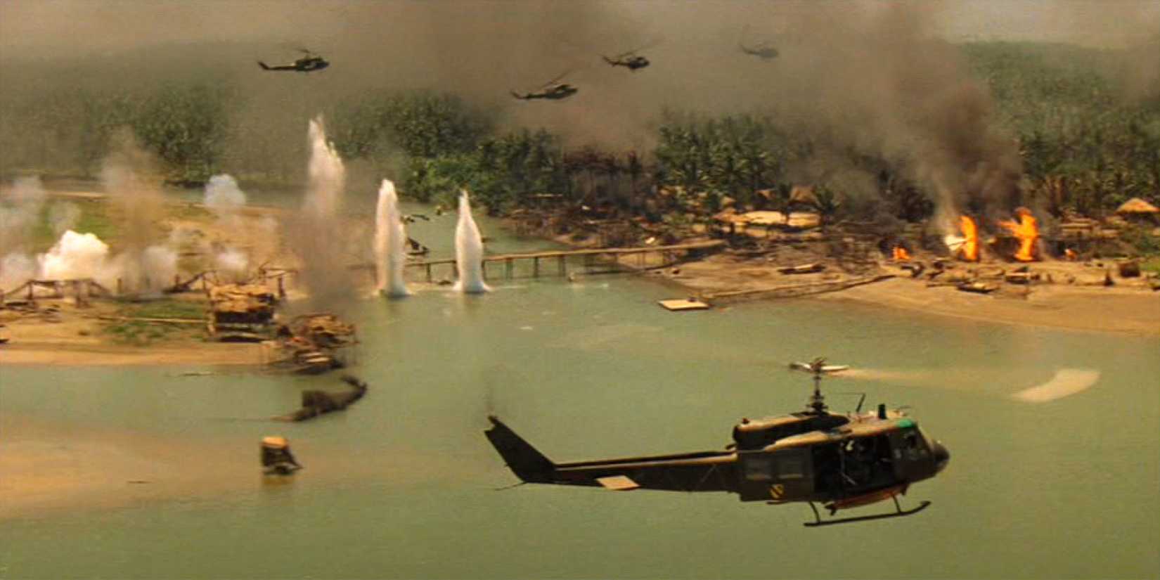 Helicopters flying over the ocean as fires blaze on land and bombs explode in Apocalypse Now