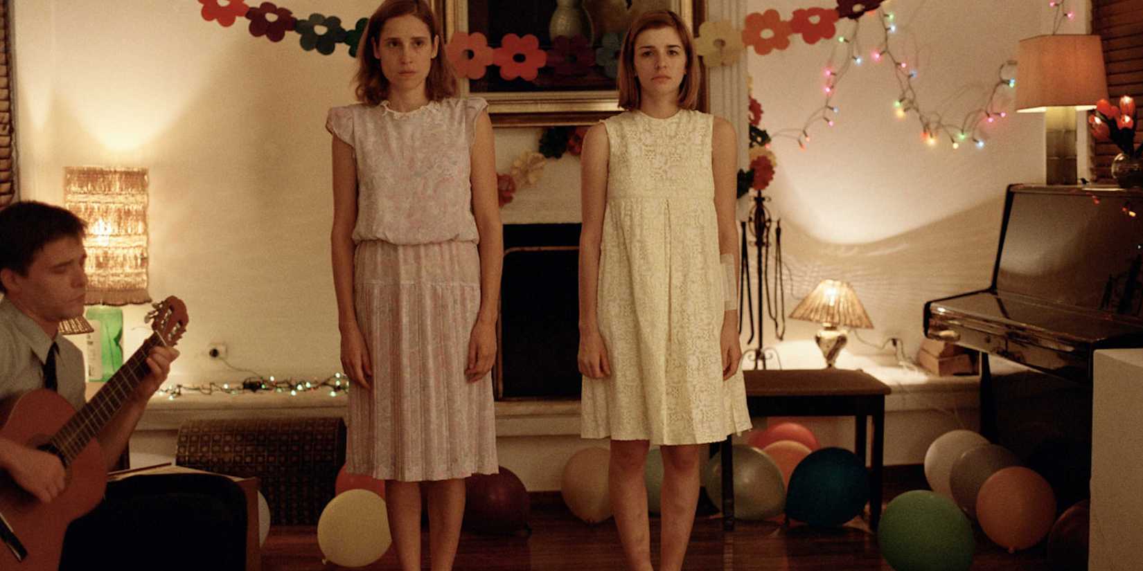 Angeliki Papoulia & Mary Tsoni as Older & Younger Daughter stand side by side, looking sullen in Dogtooth