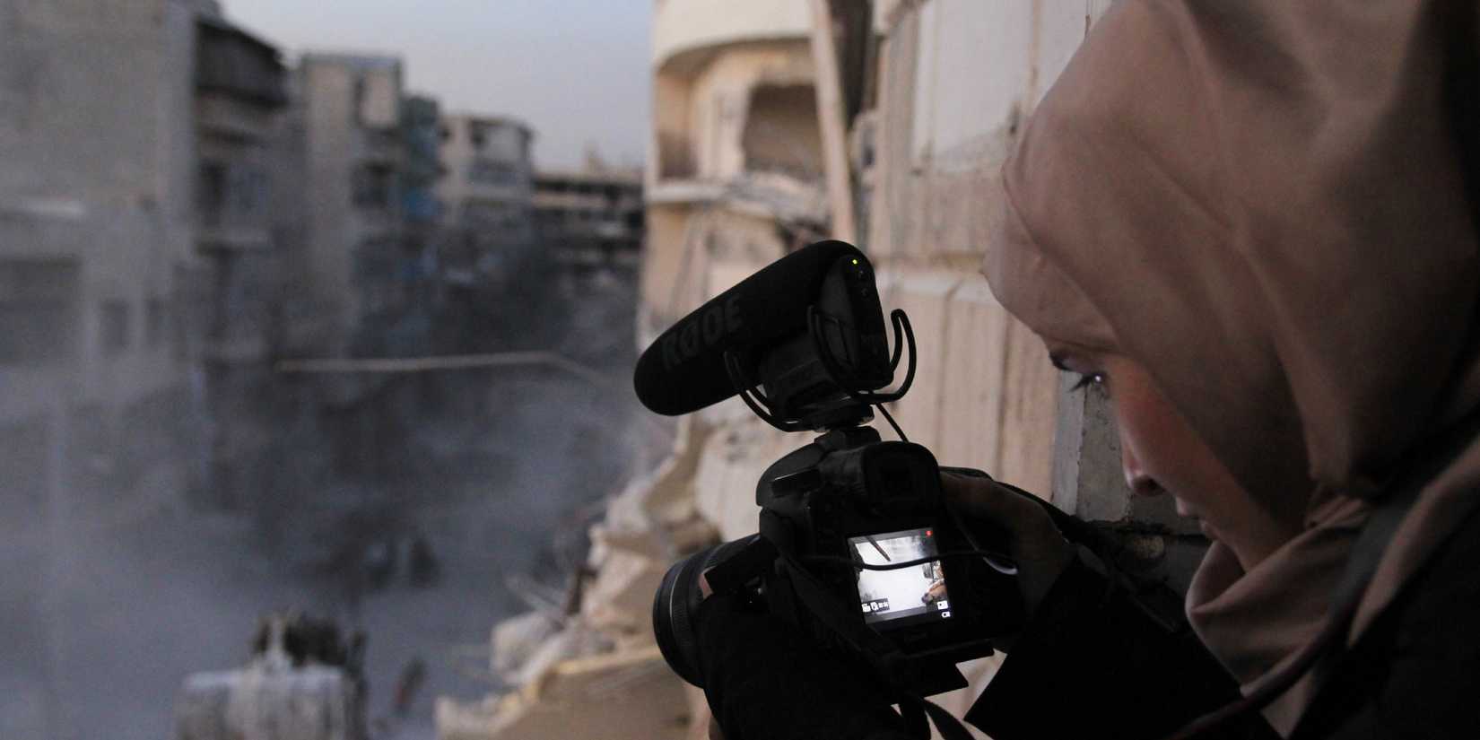 A woman recording a war zone with a camera in For Sama.