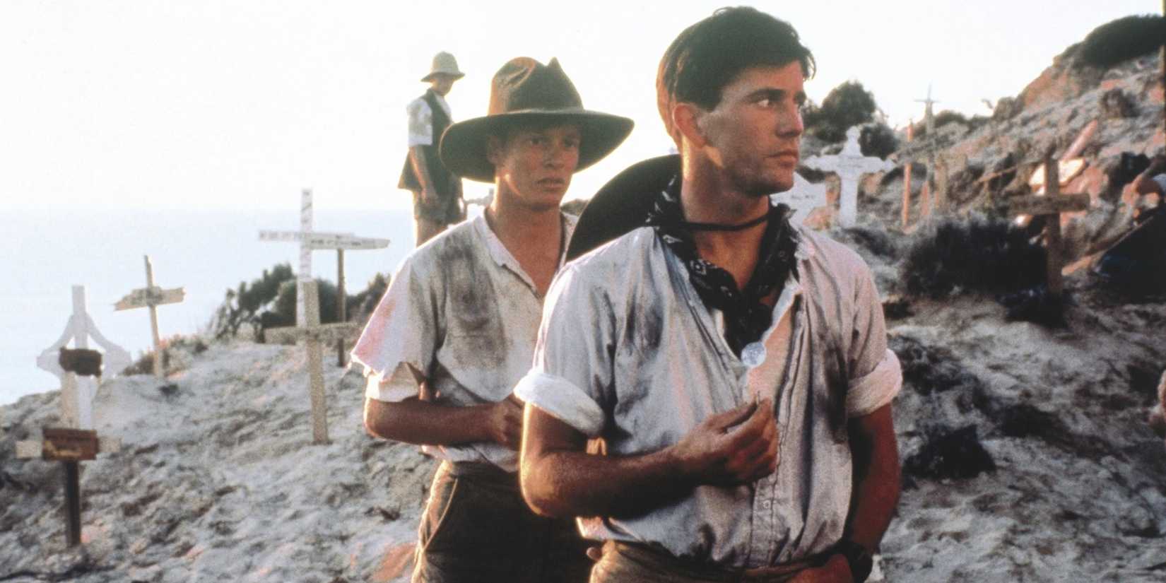 Mel Gibson looking to his left with a young man behind him in Gallipoli