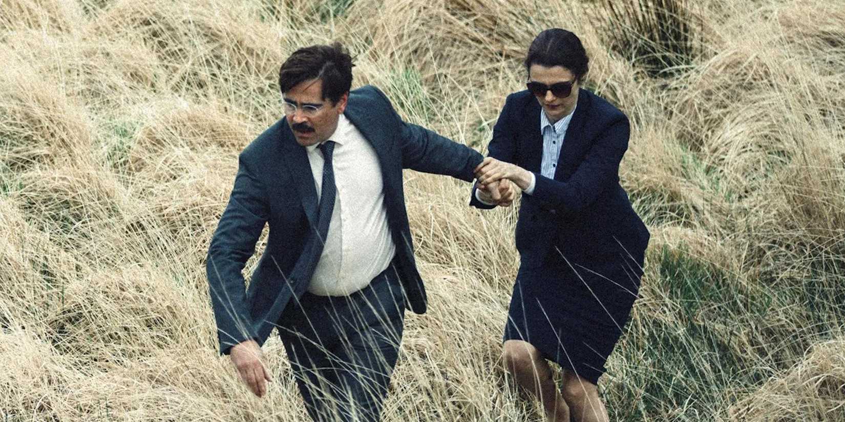 Colin Ferrell leading Rachel Weisz through a field in suits in The Lobster