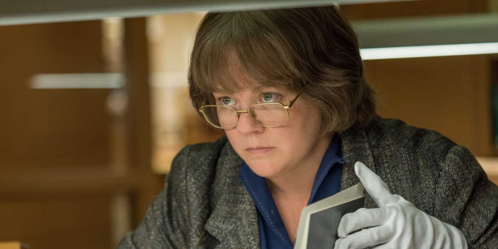 Melissa McCarthy as Lee Israel looking up while holding an open book in Can You Ever Forgive Me