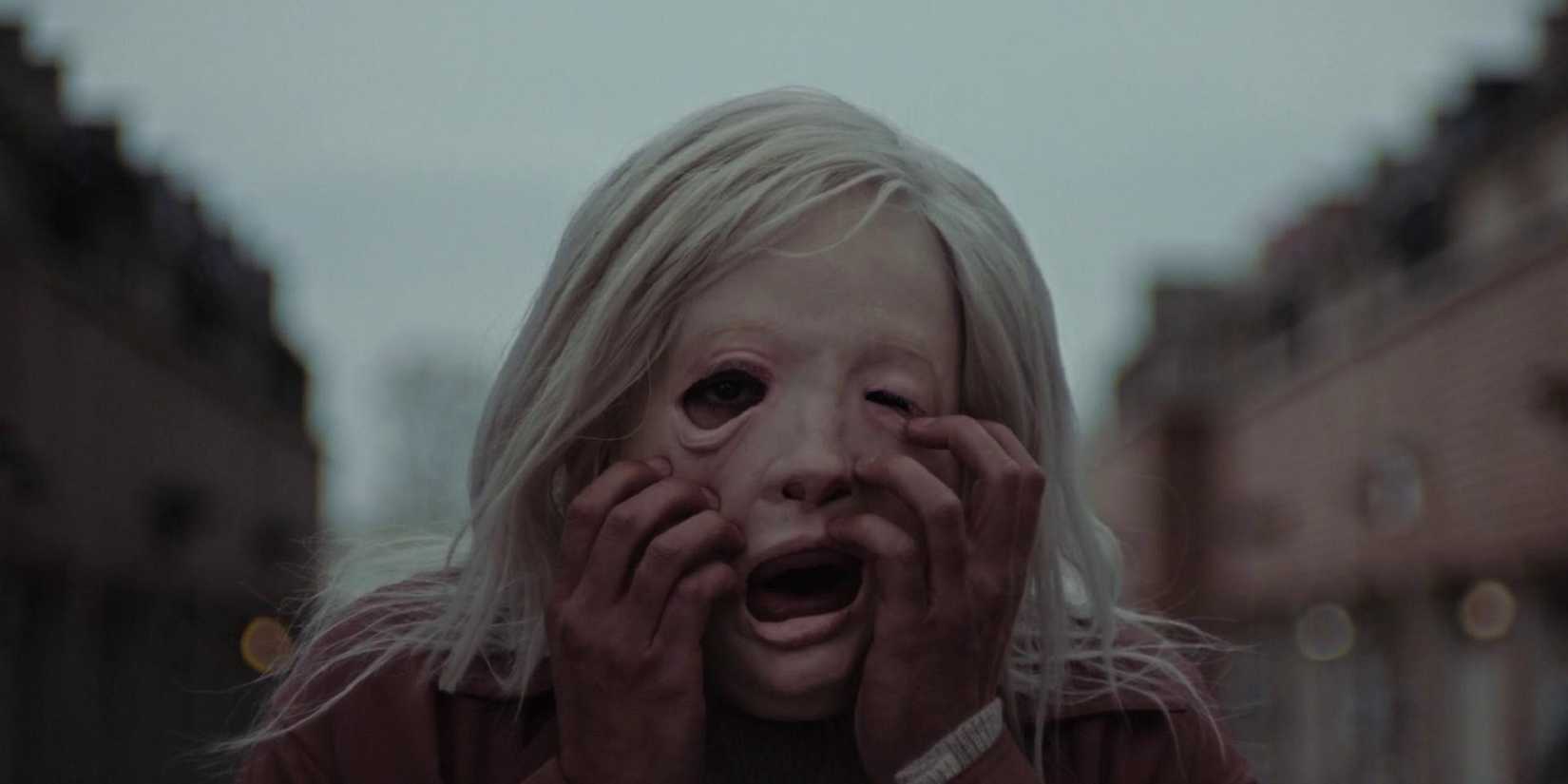 A woman trying to rip a mask off in the movie Possessor.