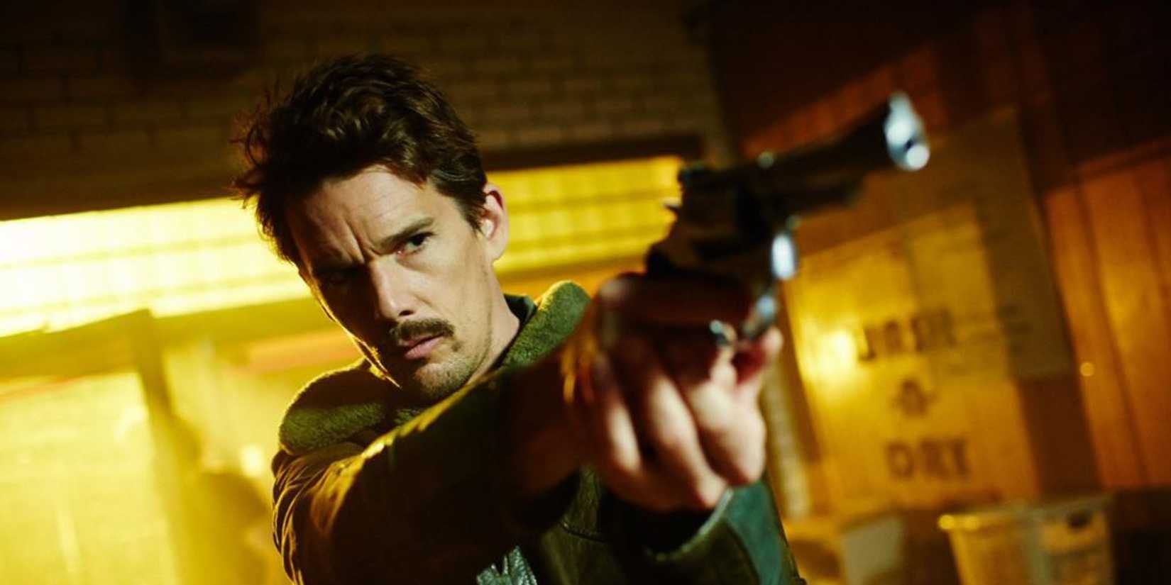 Ethan Hawke as Agent Doe aiming his gun at a person offscreen in Predestination