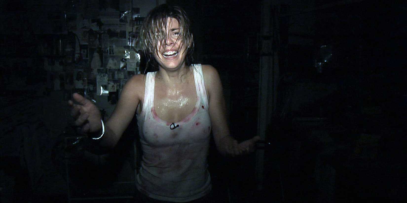 A crying woman walking down a dark hallway in [REC]