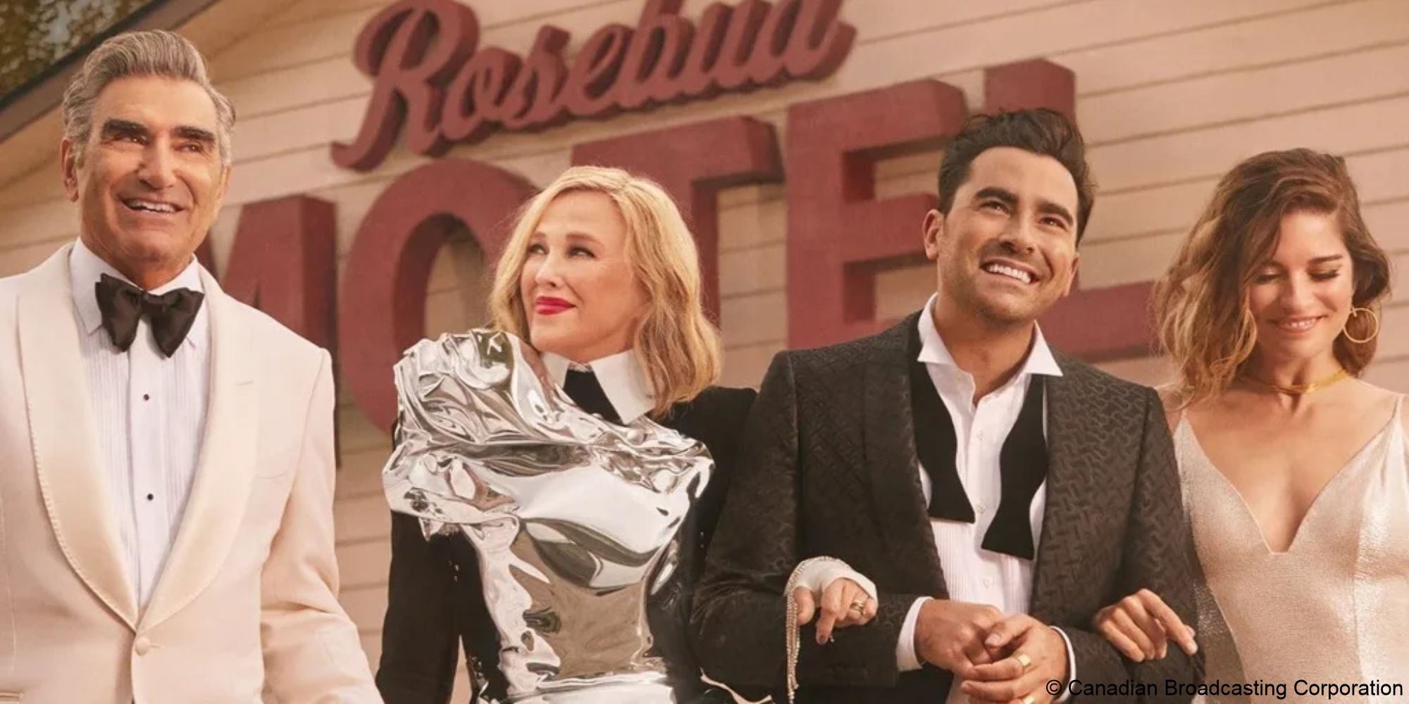 Johnny, Moira, David, and Alexis Rose stand in front of the Rosebud Motel smiling