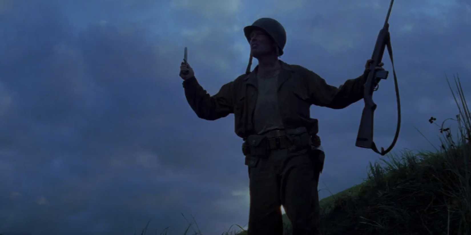A soldier stands in a field holding a gun in The Thin Red Line