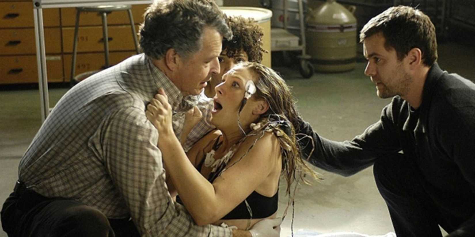 John Noble holds Anna Torv, who is scared, while Joshua Jackson and Jasika Nicole are nearby in Fringe