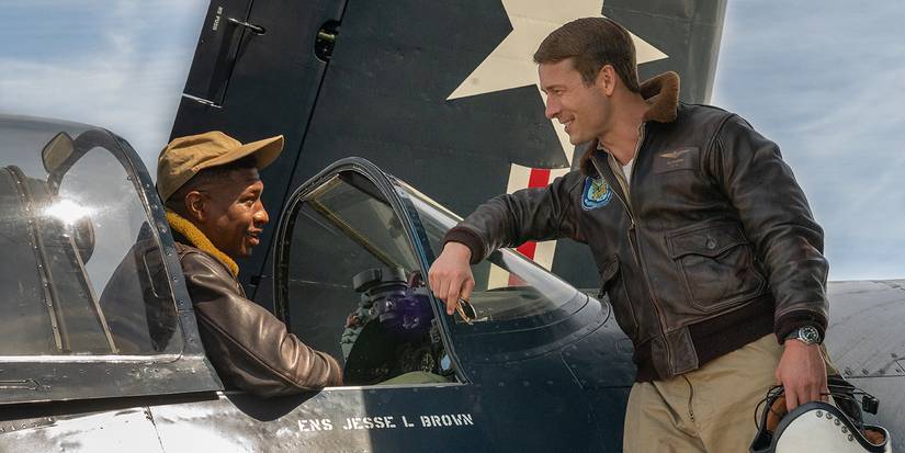 Glen Powell talks to Jonathan Majors, who sits in the cockpit of a fighter plane in Devotion.