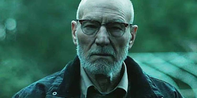 Patrick Stewart con vasos y de pie afuera mira la cámara en la habitación verde.