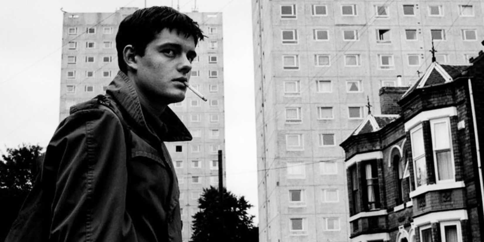 A man smoking a cigarette in front of buildings in Control 