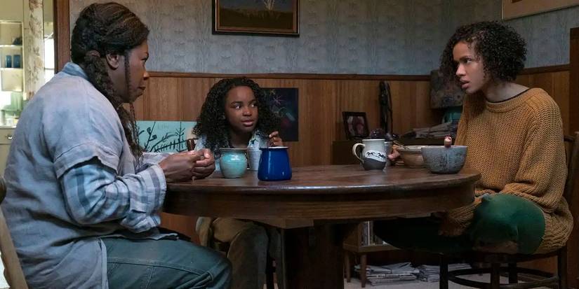 A superhuman woman on the run sits at a table in her childhood home with her mother and daughter in Fast Color.
