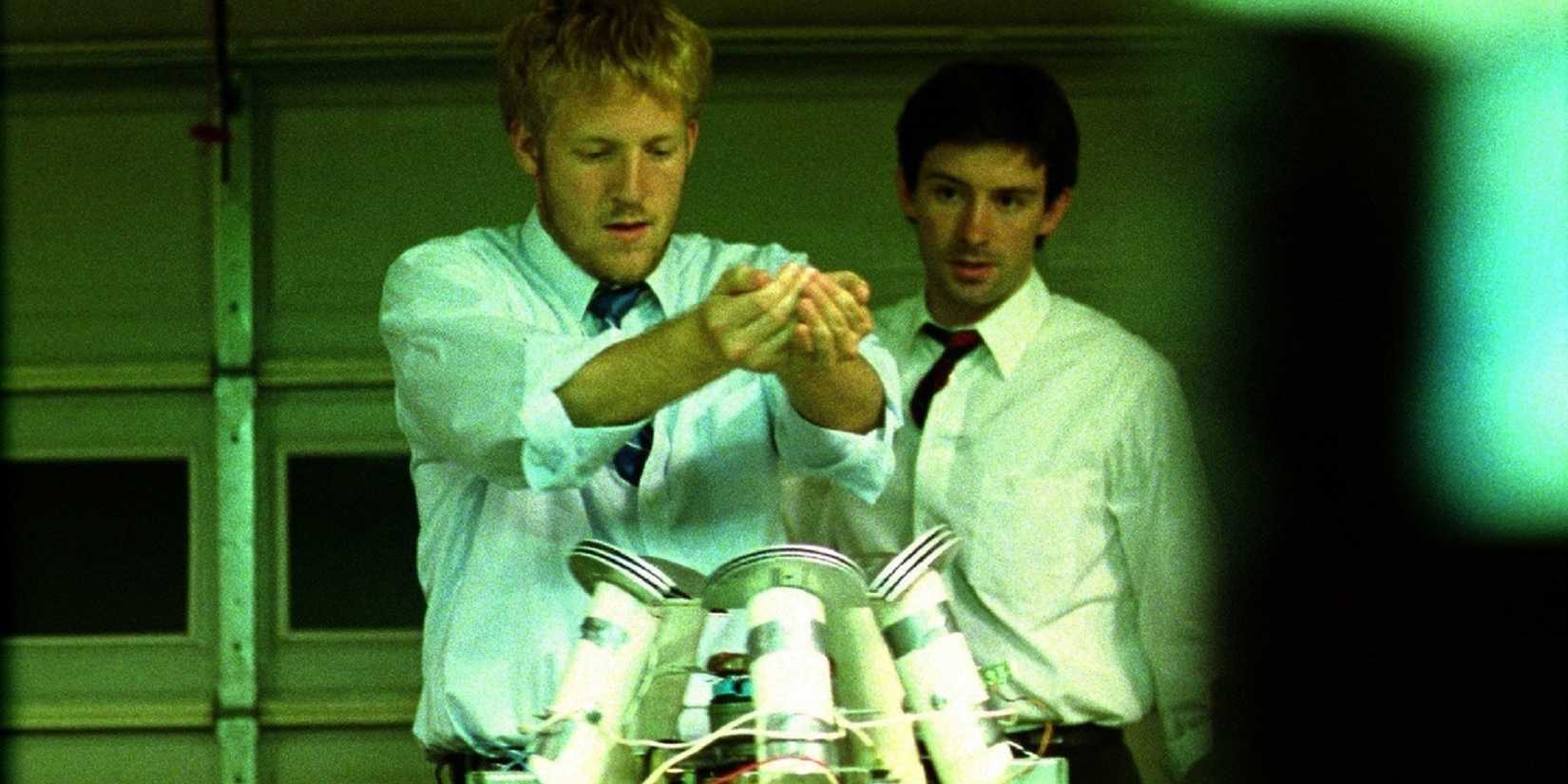 Shane Carruth as Aaron and David Sullivan as Abe looking at a machine in Primer.