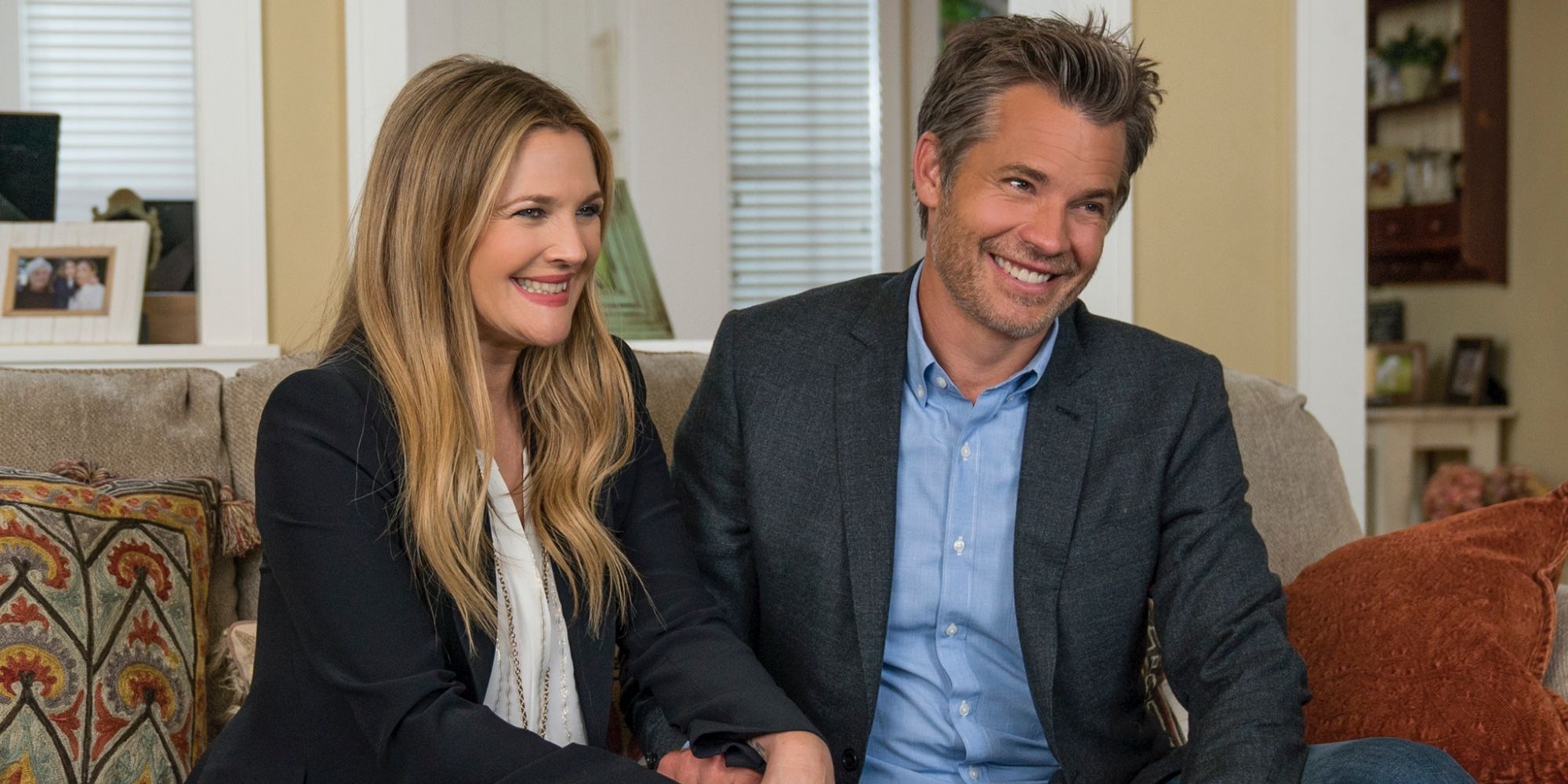 Sheila and Joel smiling and holding hands on the couch in Netflix's Santa Clarita Diet.