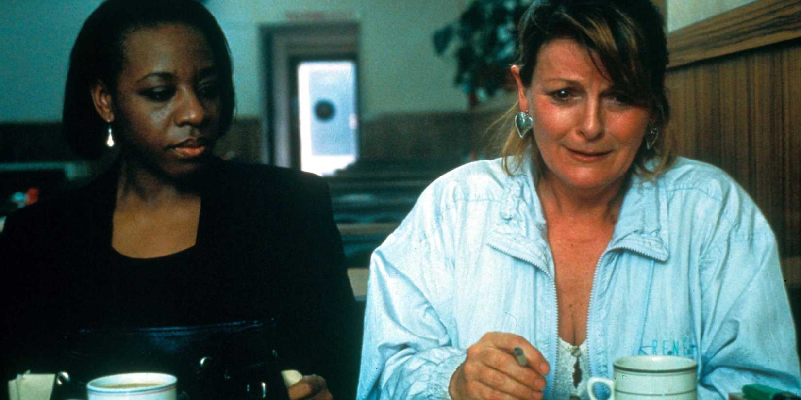 Two women sit next to each other in a diner and one looks troubled in Secrets & Lies