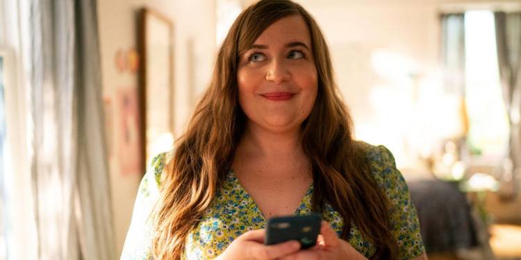 Annie smiling while holding her phone in Shrill.