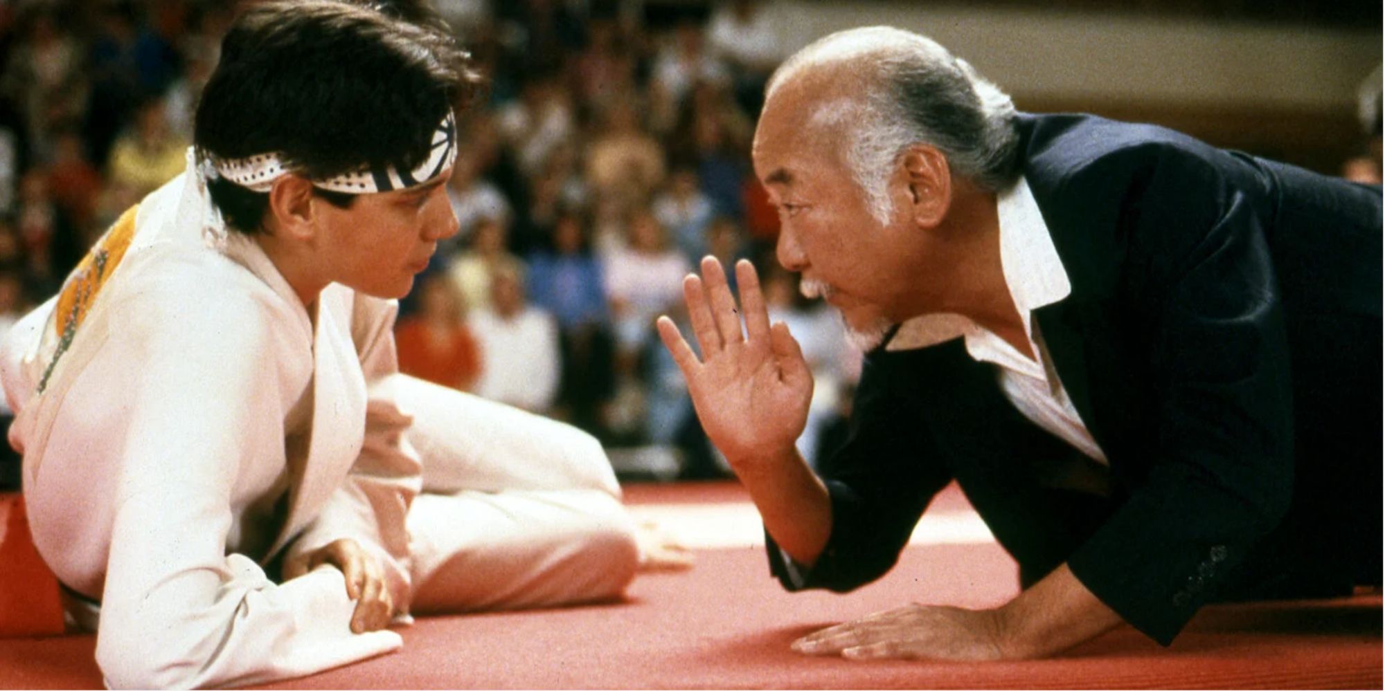 Ralph Macchio and Noriyuki Morita talking on a mat during the tournament
